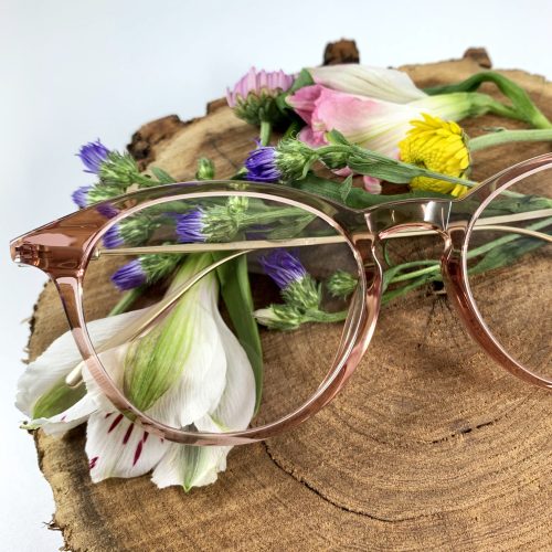 A pair of stylish frames rests on a bed of flowers.